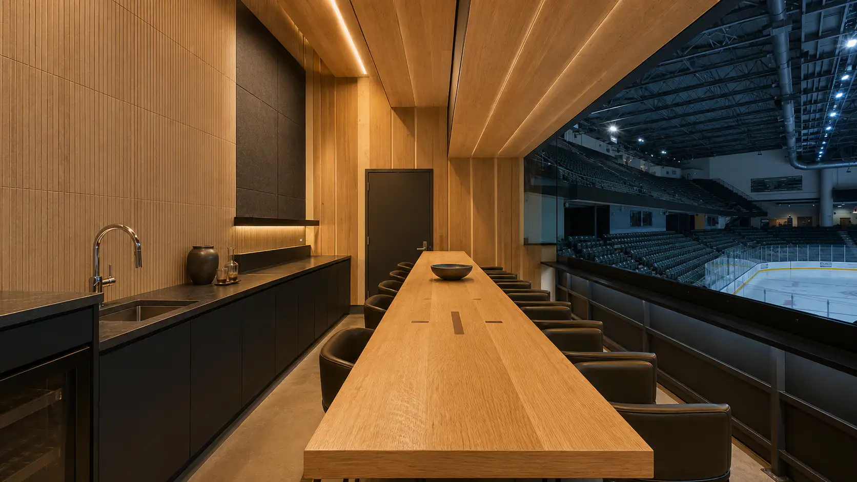 A long white oak bar top in a private suite above an arena